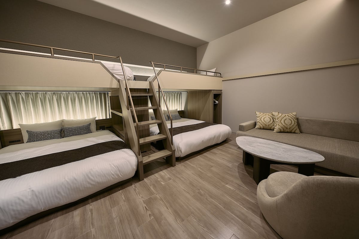 A modern hotel room with a bunk bed, a sofa, and a coffee table.