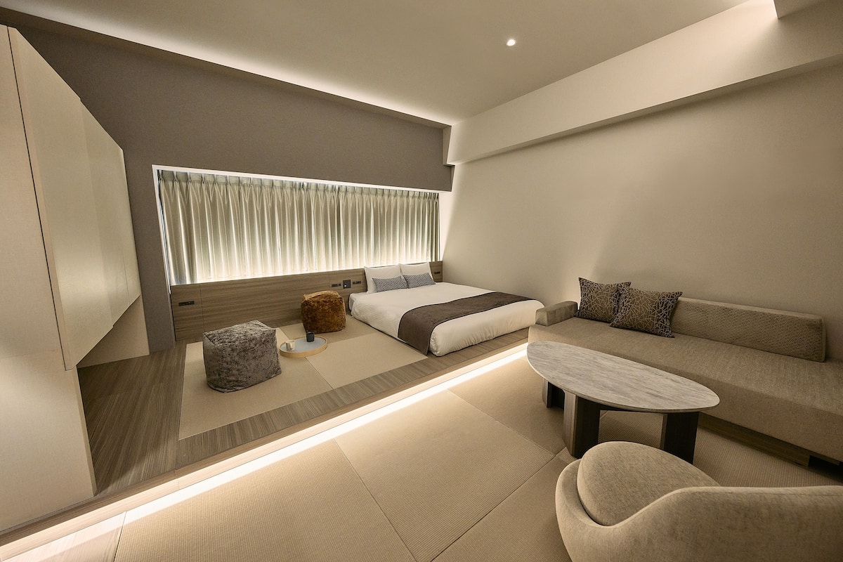 A modern bedroom with a bed, sofa, and a small table.