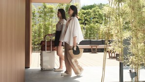Two people walking towards a modern building entrance with a wooden floor and a view of bamboo plants. - fav HIROSHIMA STADIUM (Hiroshima)