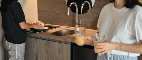 Una cocina moderna con encimera de madera, pileta de acero inoxidable y un espejo redondo sobre la pileta.