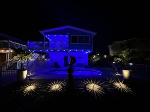 Ein zweistöckiges Haus mit Balkon, Schwimmbad und Statue.