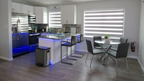 A modern kitchen with a built-in island, stainless steel appliances, and a dining area with a glass table and chairs. - Tropical Dream Vacation with 3 bdrm/2 baths, pool & dock - On Sombrero Beach Rd! (Marathon)