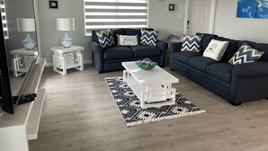 A modern living room with two dark blue sofas, a white coffee table, and a patterned rug. - Tropical Dream Vacation with 3 bdrm/2 baths, pool & dock - On Sombrero Beach Rd! (Marathon)