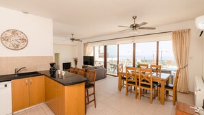 A modern kitchen with wooden cabinets, a black countertop, and a dining area with wooden chairs and a table. - Villa Oleander - 4 bedroom Villa with Private Heated Pool, Hot Tub, Stunning Views (Paphos)