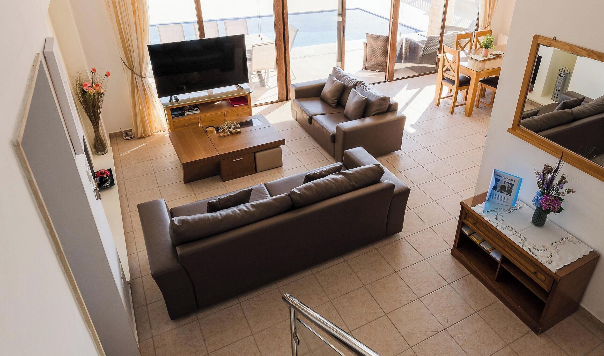 Una sala moderna con sofá, televisor y comedor con mesa y sillas.