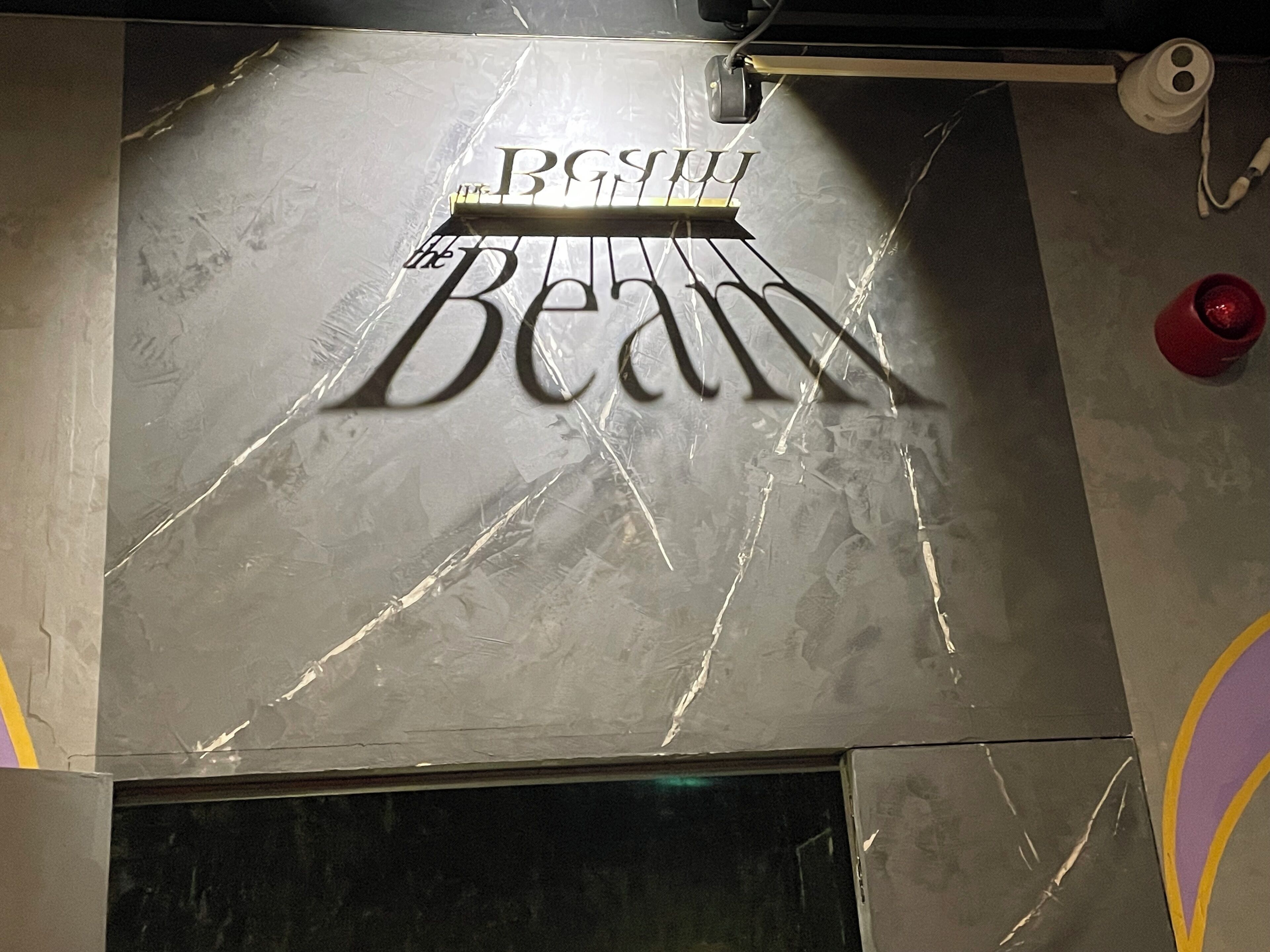 A wall with a reflective surface and the words "BGSU" and "the Beam" in a stylized font.
