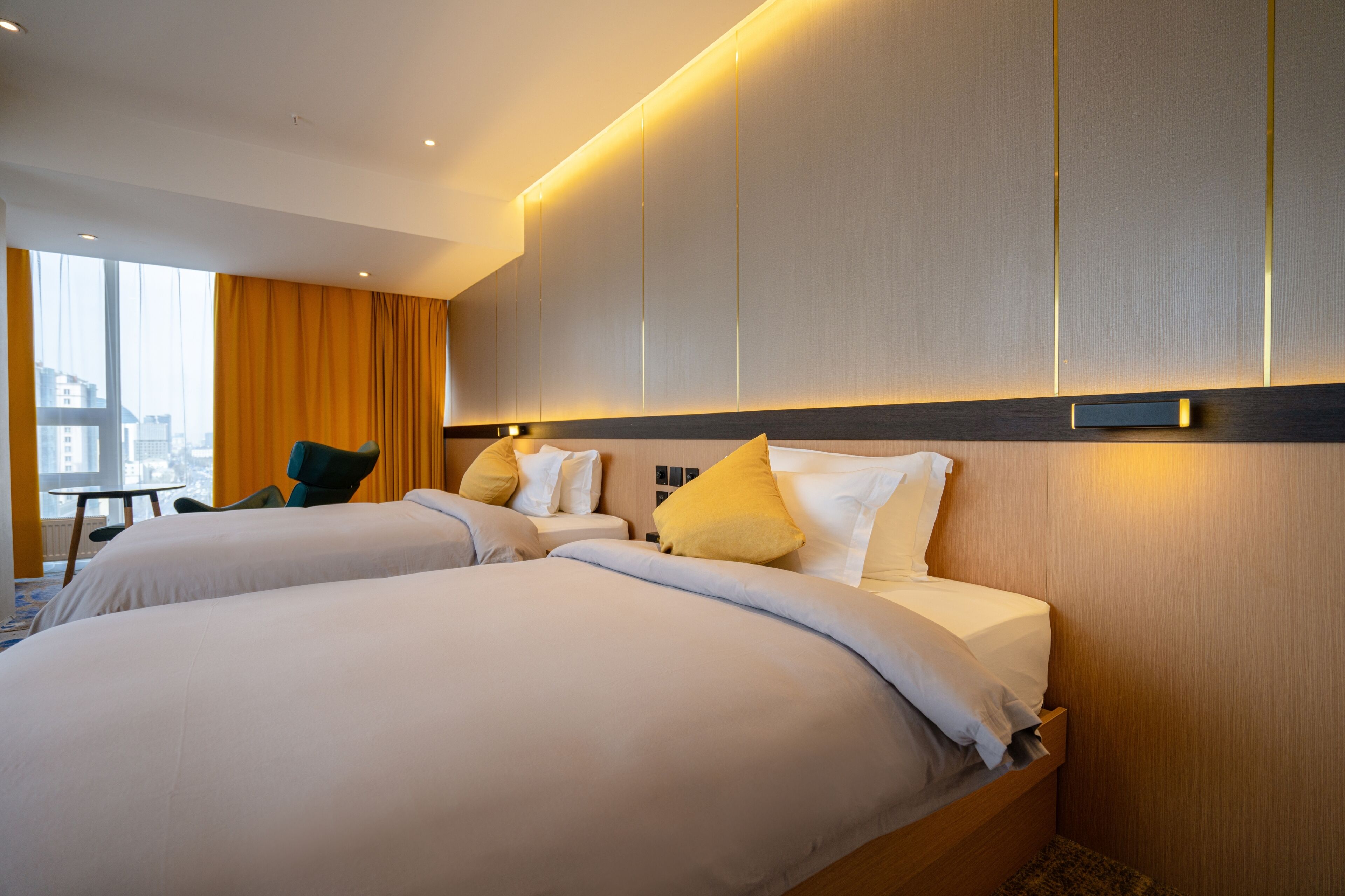Een hotelkamer met twee bedden, een bureau en een stoel.