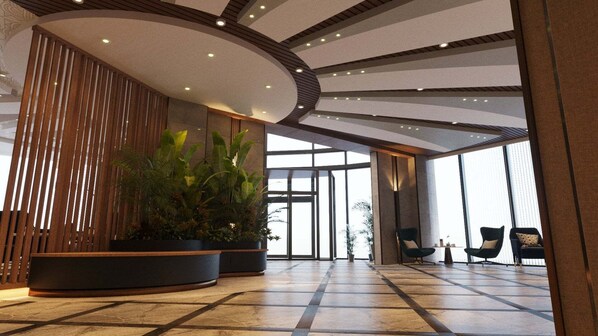 A spacious lobby with a modern design, featuring a large potted plant, seating area, and a large glass entrance.