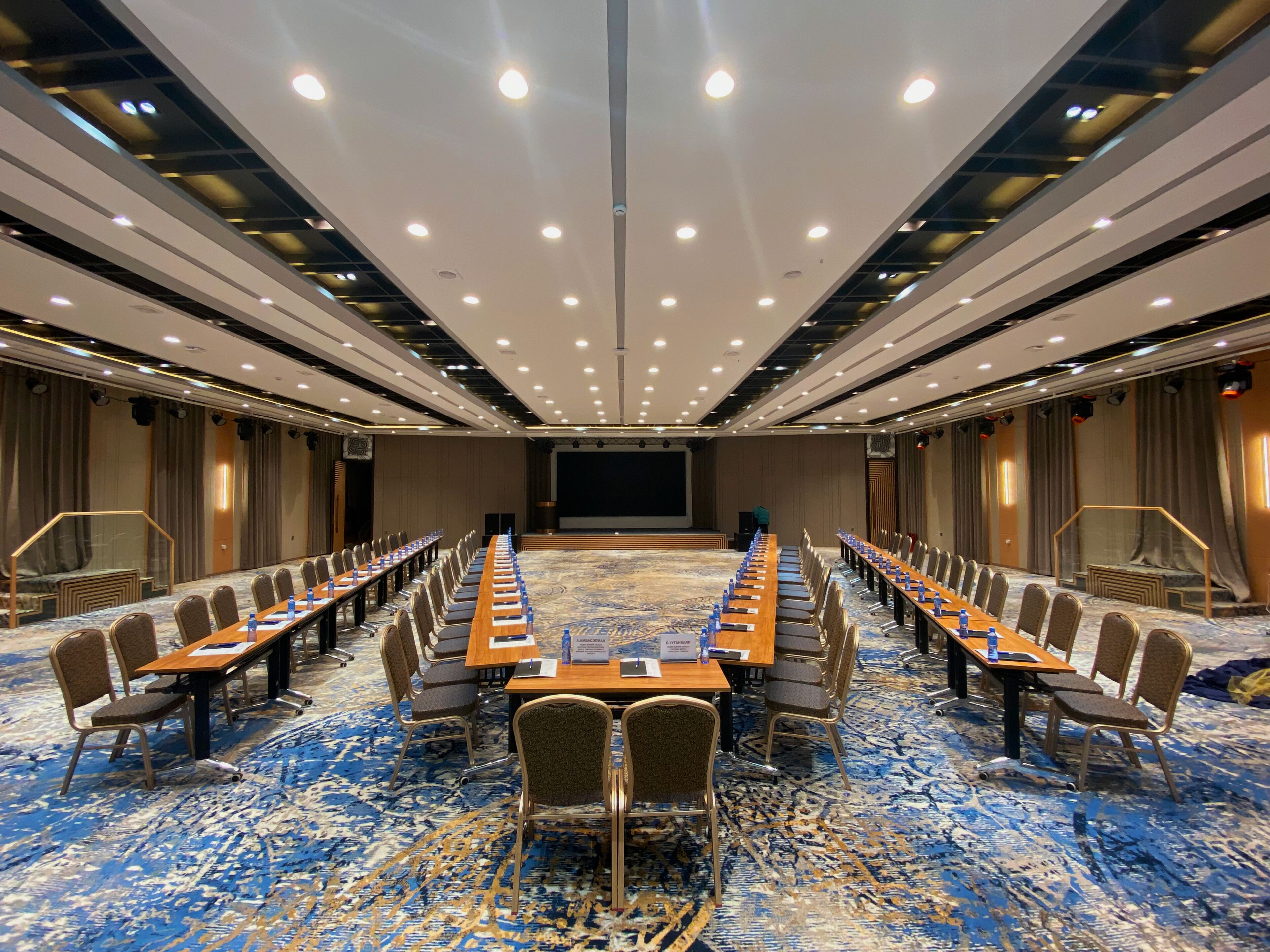 A conference room with a long table, chairs, and a stage.