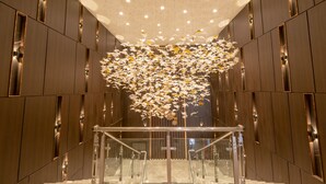 Ein modernes Interieur mit einer zentralen Treppe, Holzwandverkleidung und einer dekorativen Deckeninstallation.