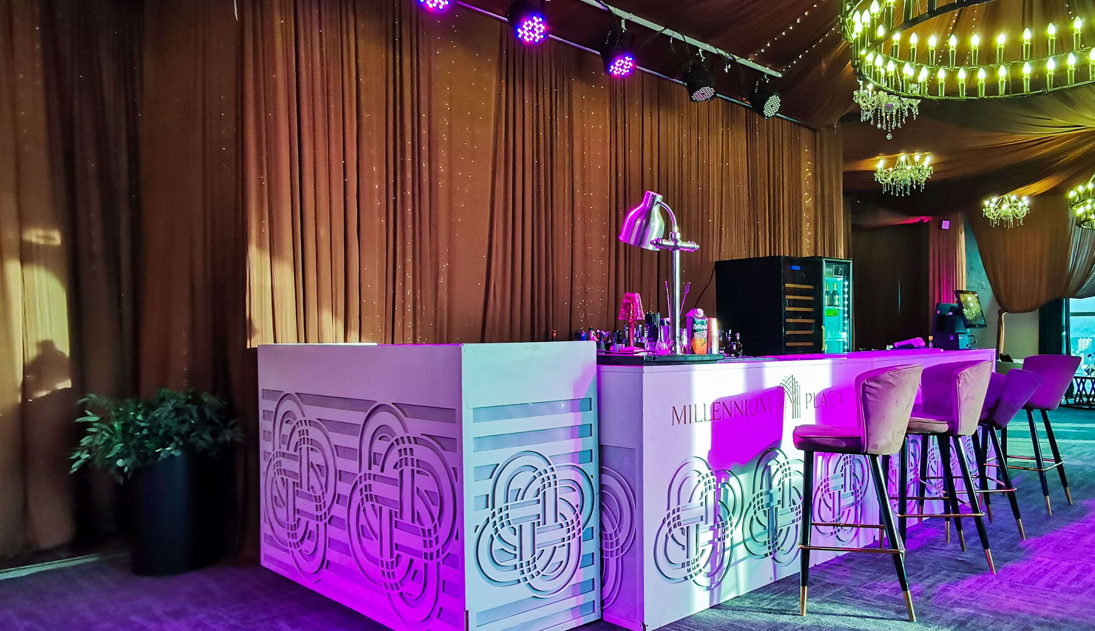 A bar area with a counter, bar stools, and a neon sign.