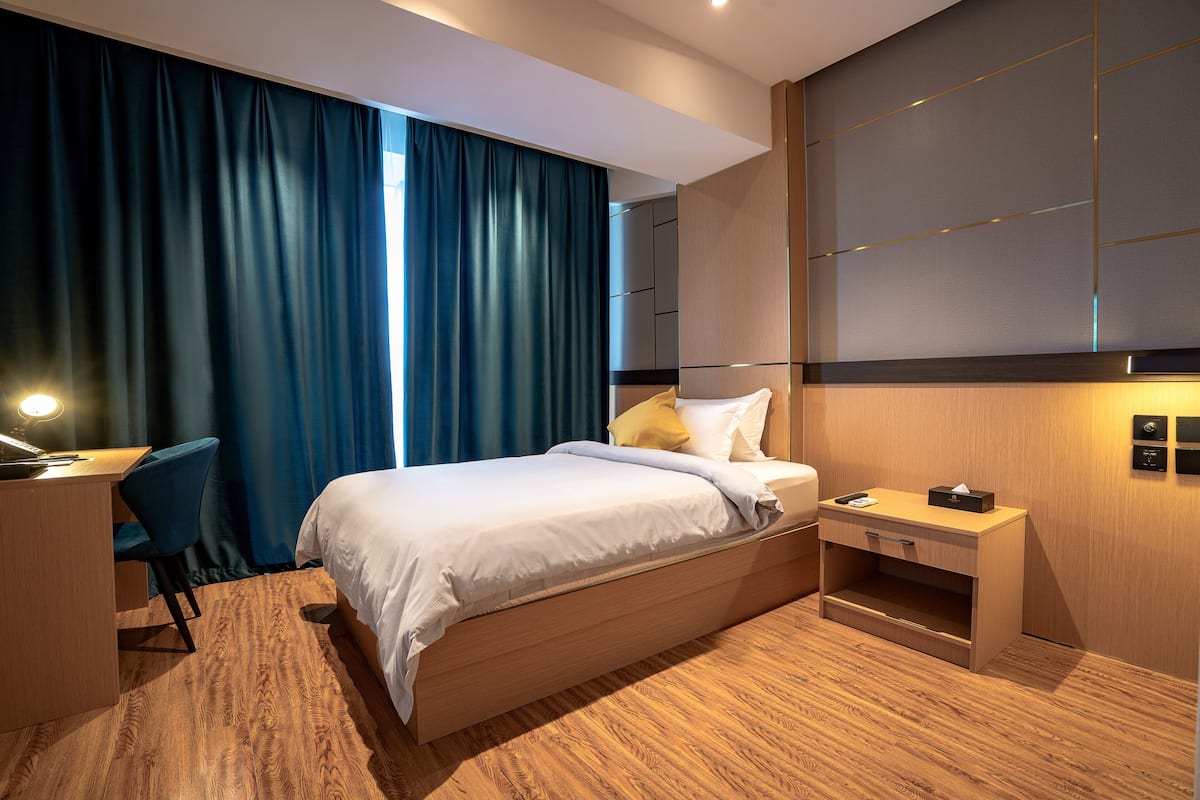 Una habitación de hotel moderna con una cama de madera, un escritorio y una silla.