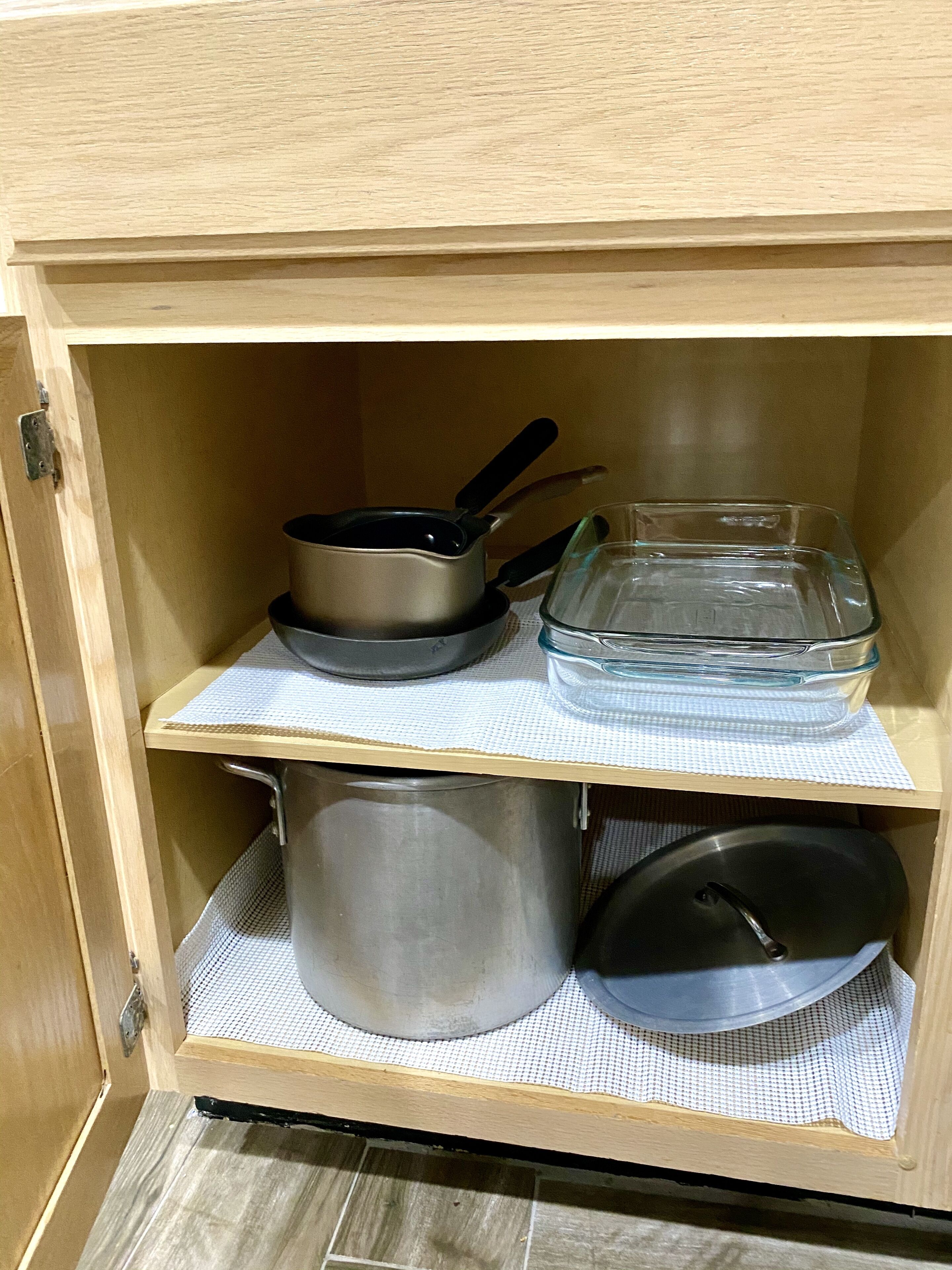 A wooden cabinet with two shelves, each holding kitchenware.