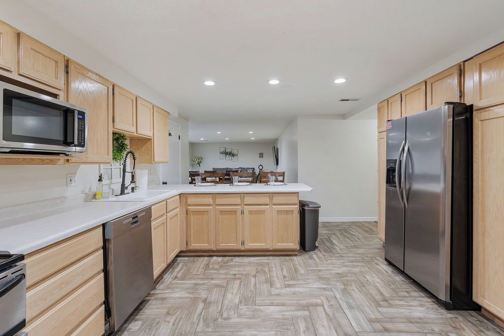 Una cocina moderna con armarios de madera, un refrigerador de acero inoxidable, un microondas y un lavavajillas.