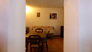 Un comedor con una mesa y sillas, un mantel con motivos florales y dos cuadros en la pared.
