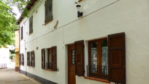 Un edificio blanco con contraventanas de madera, una puerta y un pequeño porche.