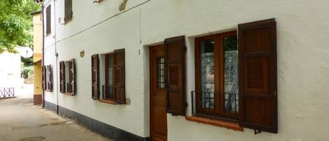 A white building with wooden shutters, a door, and a small porch area.