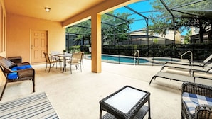 An outdoor patio with wicker furniture, a pool, and a glass enclosure. - Comfortably spacious home with a private pool, spa, and arcade. (Davenport)