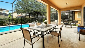 A covered patio with a pool, outdoor seating, and large windows. - Comfortably spacious home with a private pool, spa, and arcade. (Davenport)