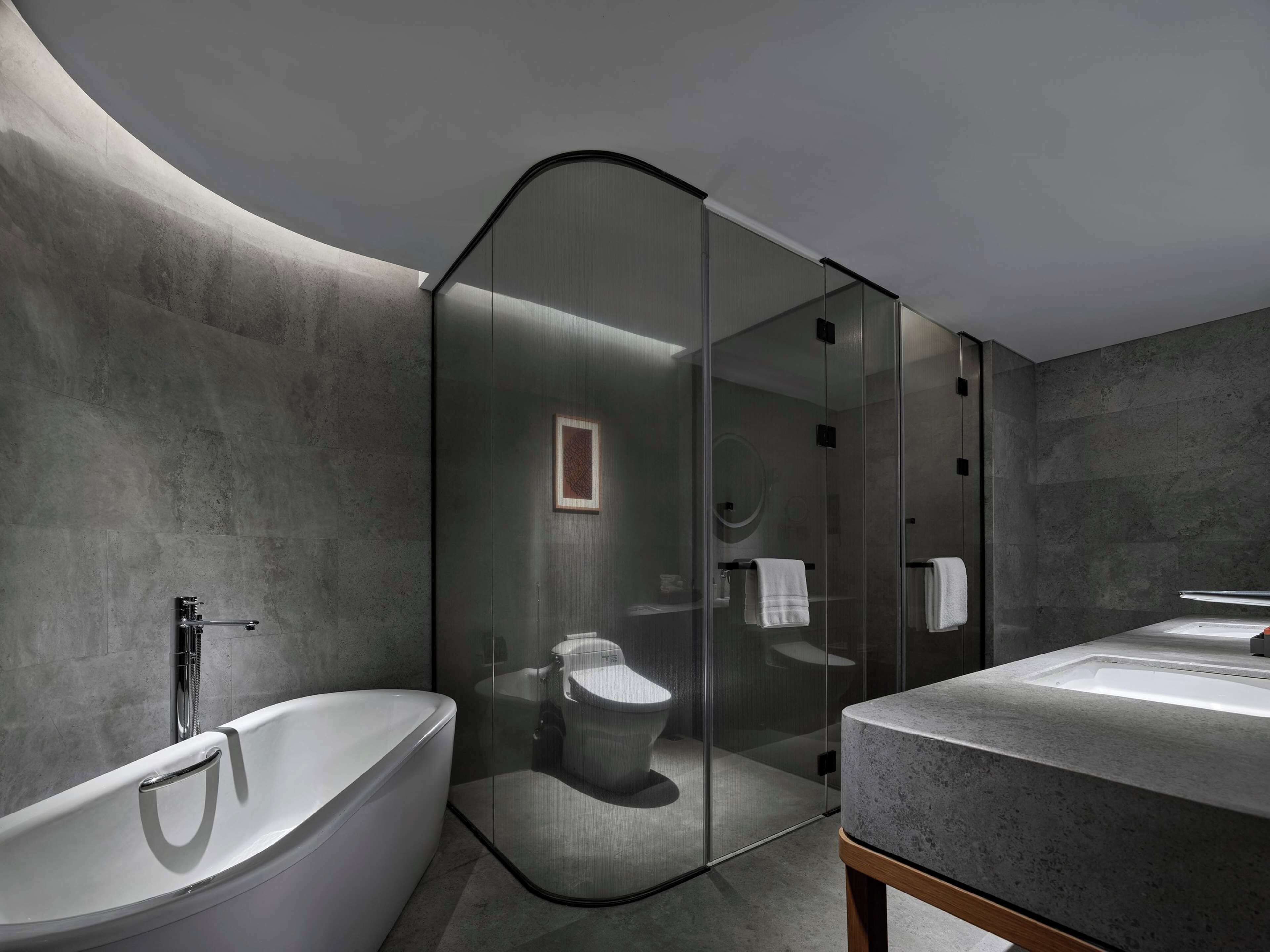 Ein modernes Badezimmer mit einer freistehenden Badewanne, einer Duschkabine und einem Waschbecken mit Granitplatte.