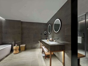 A modern bathroom with a large bathtub, a wooden vanity with a mirror, and a glass shower enclosure. - Garrya Huzhou Lucun  (Huzhou)