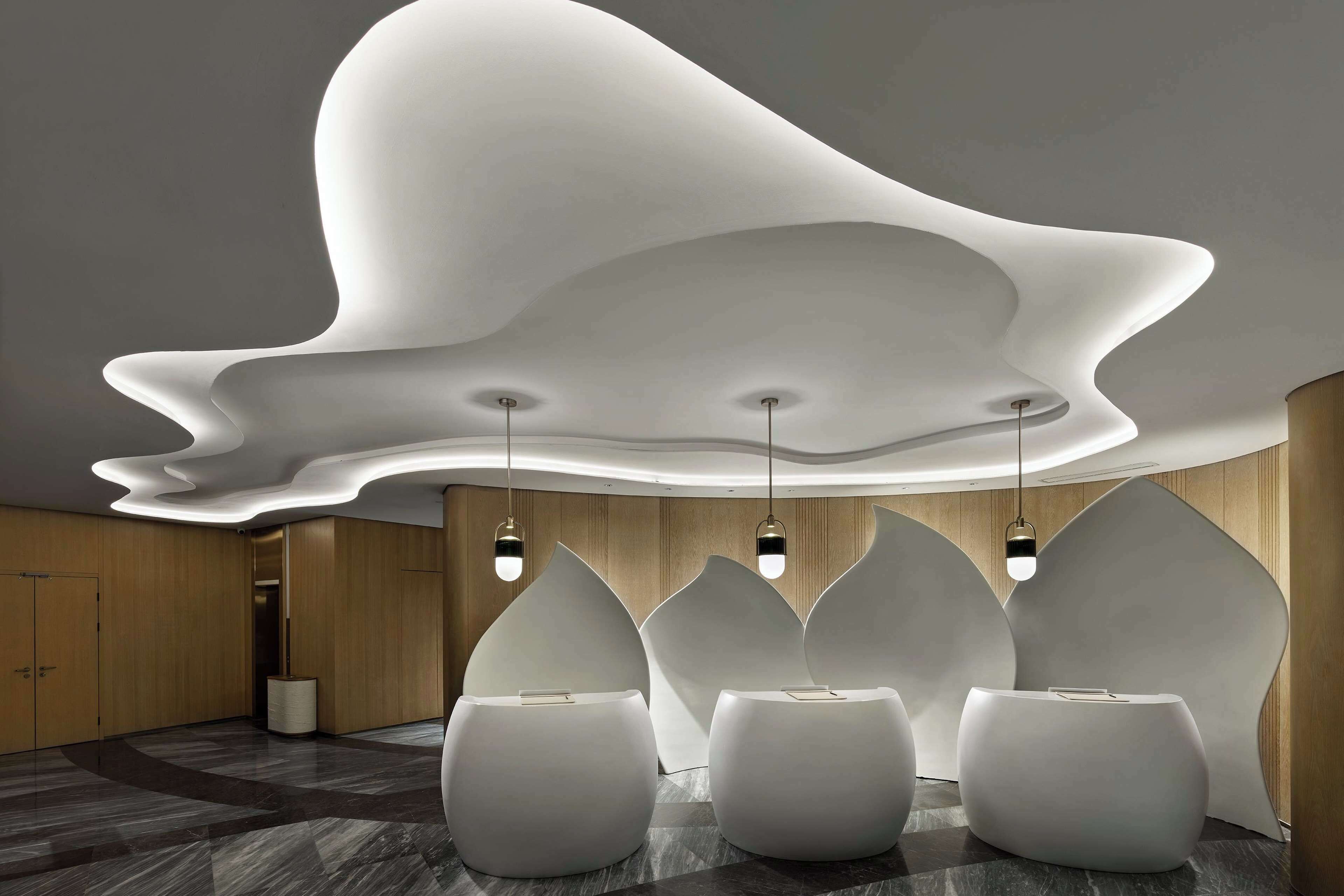 Um lobby moderno com design de teto diferenciado, áreas de estar rebaixadas e painel de parede de madeira.