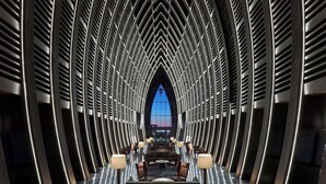 Un interno moderno con un'area salotto centrale, un'ampia finestra ad arco e un rivestimento metallico a coste.