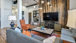 Un salon moderne doté d’un grand téléviseur à écran plat, d’un canapé, d’une table basse et d’un mur décoratif en bois.