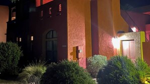 Un edificio con fachada roja y amarilla, un patio cubierto y una escalera que conduce a un nivel superior.