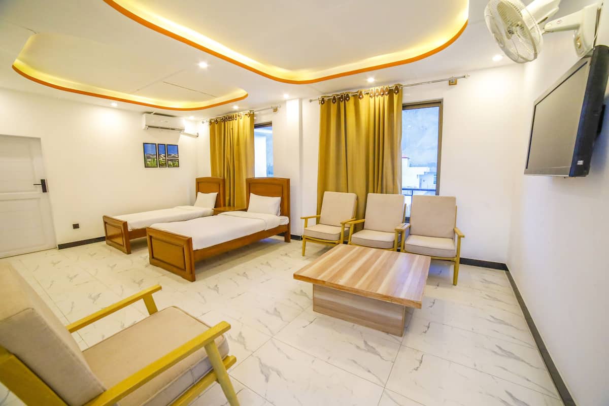 Une chambre d’hôtel avec un lit, deux chaises, une petite table et un téléviseur.
