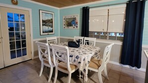 A dining area with a table set for four, surrounded by white chairs, in a room with wooden ceiling and light blue walls. - Our Happy Place! (Springfield)