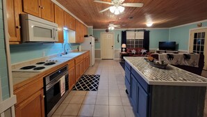 A kitchen with wooden cabinets, a microwave, stove, and a ceiling fan. - Our Happy Place! (Springfield)