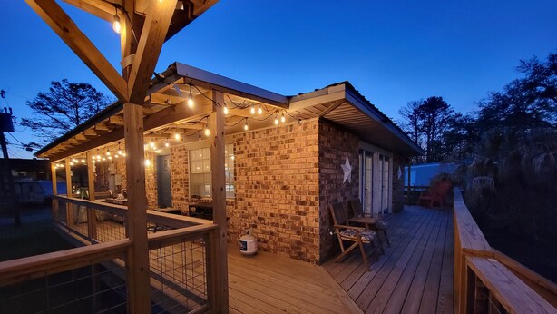 A wooden deck with a covered patio area, stone walls, and string lights. - Our Happy Place! (Springfield)