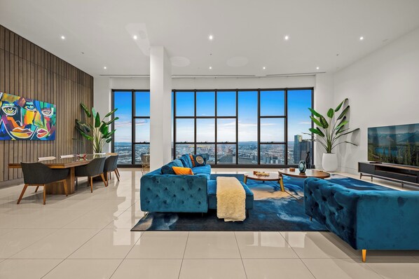 Enjoy a panoramic city view from the comfort of this stylish living room, featuring a sofa, dining area, and flat-screen TV.