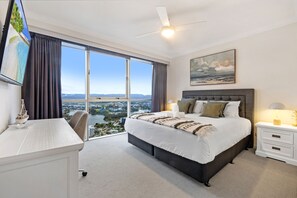 Enjoy a panoramic view of the coastline from this room's large window, featuring a comfortable bed and stylish furnishings.