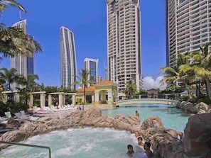 Relax by the resort's central pool surrounded by palm trees and lounge chairs.
