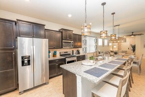 Enjoy cooking in this well-equipped kitchen with a gas stove, microwave, and refrigerator, complemented by a large island and pendant lights.
