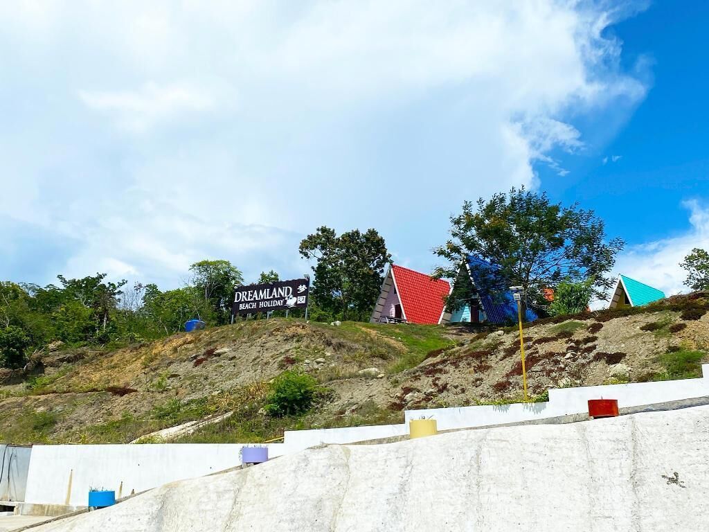 A hilly landscape with a sign for 'Dreamland Beach Holiday' and colorful buildings.