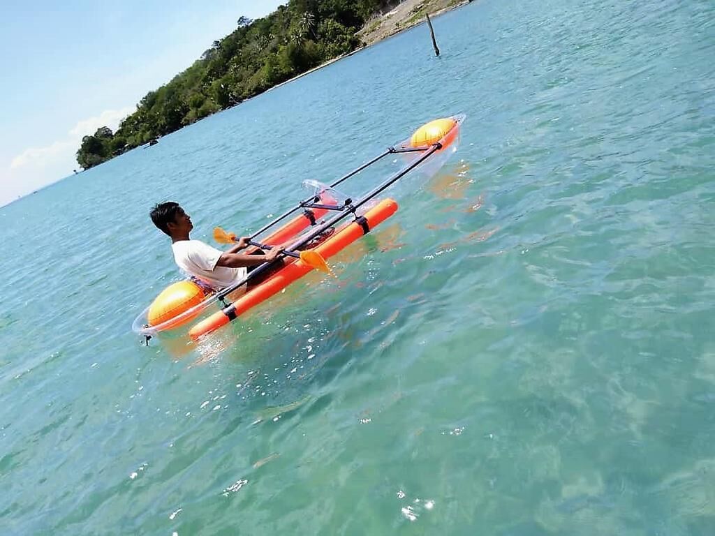 Une personne qui rame sur un petit kayak orange, sur une eau claire.