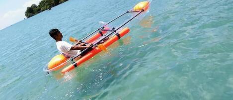 Une personne qui rame sur un petit kayak orange, sur une eau claire.