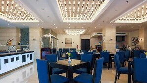 A spacious dining area with modern decor, including a central table with chairs and a bar area with seating. - The Proud Hotel (Al Khobar)