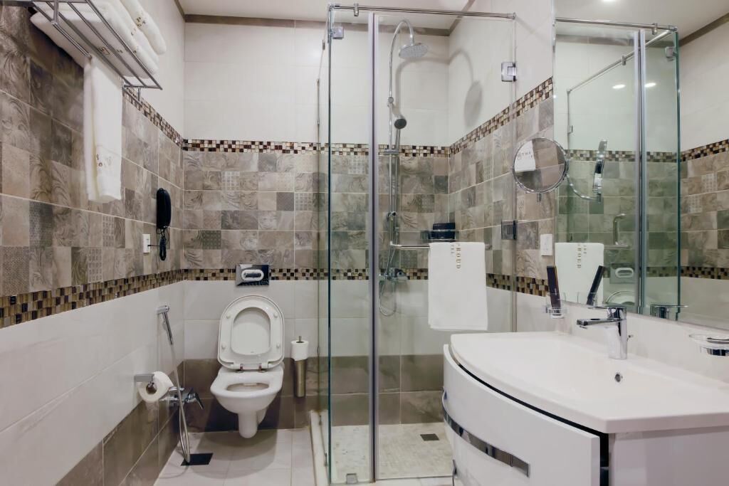 A modern bathroom with a glass-enclosed shower, a toilet, and a sink with a mirror.