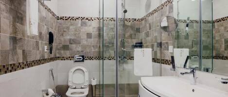 A modern bathroom with a glass-enclosed shower, a toilet, and a sink with a mirror.