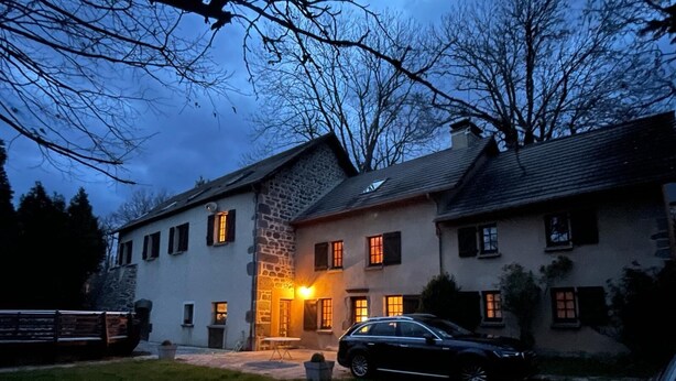 Ein großes, zweistöckiges Steinhaus mit gepflegtem Rasen und einem parkenden Auto.