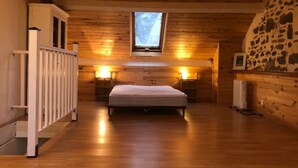 Ein gemütliches Schlafzimmer mit Holzboden, einem Bett, einem Oberlicht und einer Steinwand.