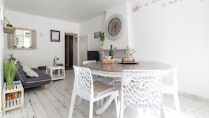 Un comedor con una mesa redonda, sillas blancas y un reloj en la pared.