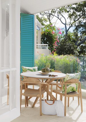 A round wooden table with chairs, a white tablecloth, and a pineapple centerpiece. - Villa Nette - ocean views, walk to beach & restaurants, National Park (Noosa Heads)