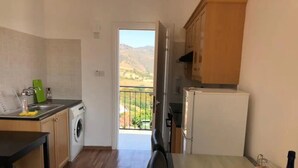 Uma cozinha compacta com máquina de lavar, geladeira e área de refeições com mesa e cadeiras.