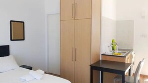 Quarto de hotel com cama, escrivaninha e guarda-roupa.