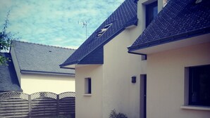 Een huis met een grindpad, een kleine tuin en een houten hek.
